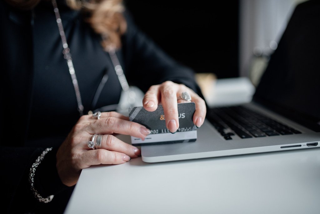 Person completing online shopping transaction using credit card at a laptop