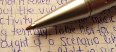 Metallic ballpen tips / biro Ballpen Ballpoint pen in silver with handwritten random blue text on quad-ruled paper