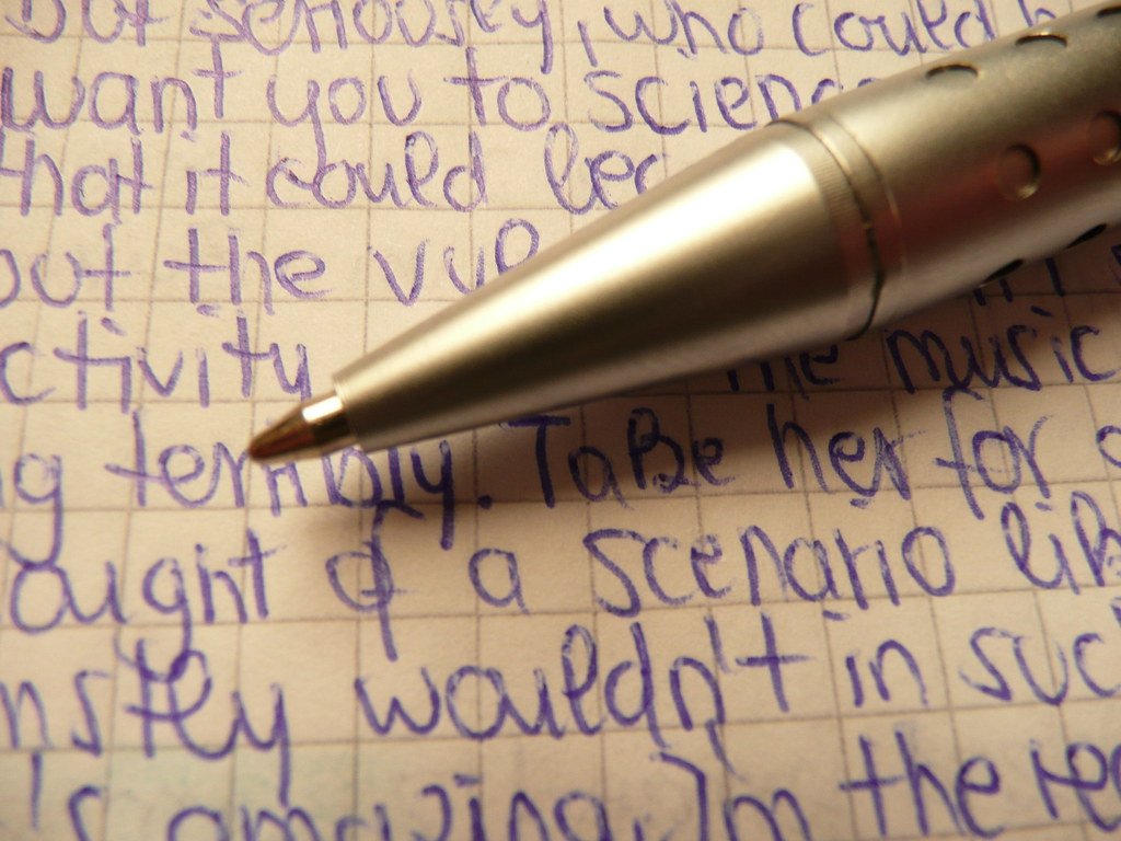 Metallic ballpen tips / biro Ballpen Ballpoint pen in silver with handwritten random blue text on quad-ruled paper
